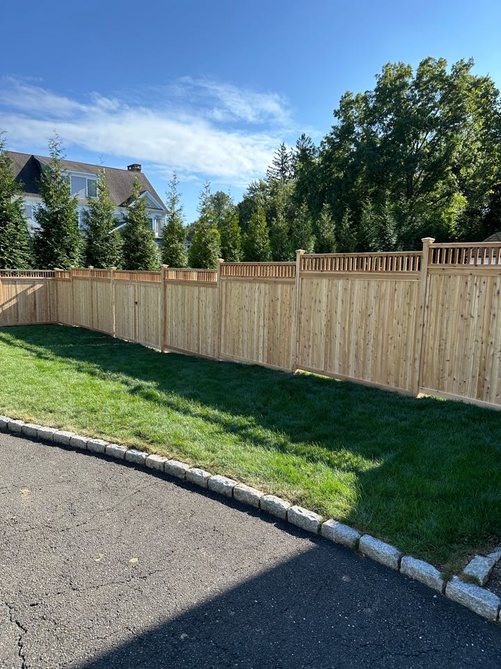 A stunning new cedar cap and trim fence in Westport with several beautiful custom details - a capped picket top and a 5 foot arbor with diagonal lattice side panels - which only enrich the classic cedar look. The unseen details matter too - our crew installed matching cedar boards along the bottom of the fence, burying portions into the ground to protect our customer’s dogs, keeping them safely inside.